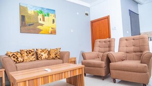 A living room with a sofa, two armchairs, a wooden coffee table, and a painting on the wall. - Guest Pride Hotel Kano  (Kano)