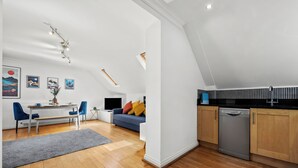 Eine moderne Küche mit Geschirrspüler, Holzschränken und einem Essbereich mit Tisch und Stühlen.