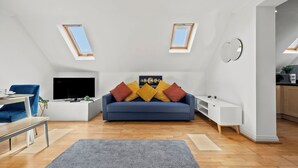 Ein modernes Wohnzimmer mit einer Couch, einem Fernseher und Oberlichtern.