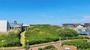 Een modern gebouwcomplex met een centrale groene heuvel, paden en een bankje.