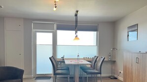 A dining area with a table, chairs, and a pendant light. - App Sylter Welle Westerland (Westerland)