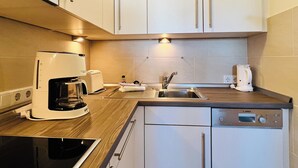 A modern kitchen with a built-in dishwasher, a coffee maker, and a toaster. - App Sylter Welle Westerland (Westerland)