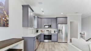 A modern kitchen with grey cabinets, stainless steel appliances, and a light wood floor. - Pleasant Peachy Escape (New Orleans)