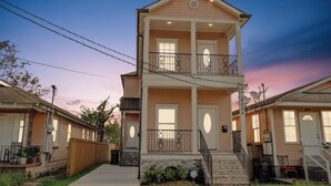 A two-story building with a balcony, a front porch, and a staircase leading to the second floor. - Pleasant Peachy Escape (New Orleans)