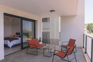 A balcony with a bed, a table, and four chairs.