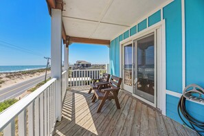 Eine Holzterrasse mit GelĂ€nder, einer Bank und Blick auf Strand und StraĂe.