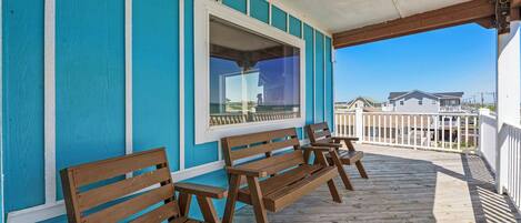 A wooden deck with benches, a window, and a view of houses in the background.
