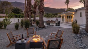 An outdoor seating area with a fire pit, chairs, and a table.