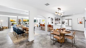 A spacious kitchen with modern appliances, a dining area with a round table, and a living area with a large window.