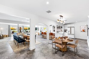 A spacious kitchen with modern appliances, a dining area with a round table, and a living area with a large window.
