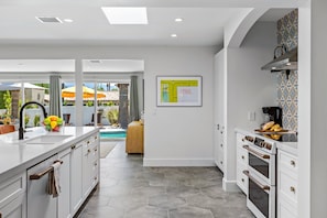A modern kitchen with white cabinetry, a central island, and a view of a swimming pool.