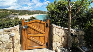 Una verja de madera con vista a una playa y montañas al fondo.