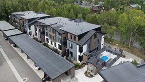 A modern residential area with multi-story houses, a swimming pool, and a view of the surrounding hills. - River West 814-Riverfront Silverthorne Condo, Fireplace, Hot Tub, Private Patio (Silverthorne)