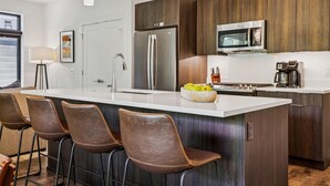 A modern kitchen with a large island, stainless steel appliances, and bar stools. - River West 814-Riverfront Silverthorne Condo, Fireplace, Hot Tub, Private Patio (Silverthorne)