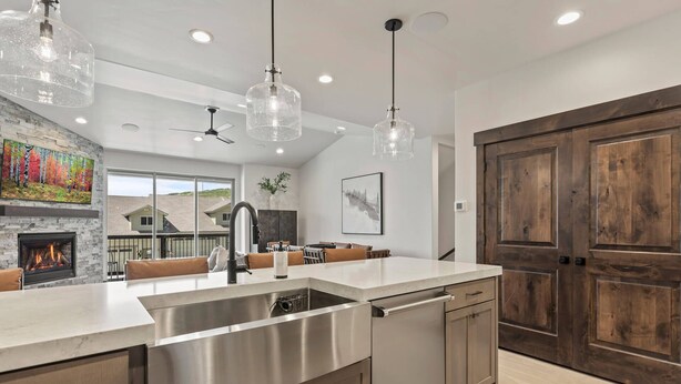 A modern kitchen with a large island, stainless steel appliances, and pendant lighting.