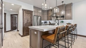 A modern kitchen with a central island, stainless steel appliances, and pendant lighting.