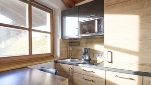A kitchen with wooden cabinets, a stainless steel microwave, and a coffee maker. - Landhaus Eichenhof (Saalbach-Hinterglemm)