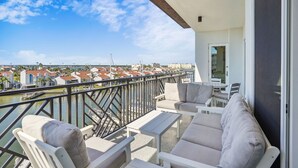 Un balcon aménagé avec un canapé, des chaises et une table, d’où l’on a vue sur une marina et des immeubles.