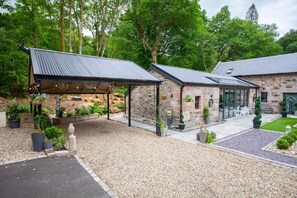 Un bâtiment en pierre doté d’un patio couvert, d’un espace extérieur aménagé pour s’asseoir et de plantes en pot.