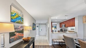 A modern kitchen with wooden cabinets, a central island, and a dining area with a bench and table. - Oceanfront Villa w/ Private 2nd Floor Balcony (Hilton Head Island)