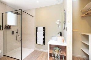 Bathroom features a glass-enclosed shower, sink, and towel rack.