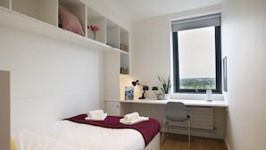 A bedroom with a bed, a desk, a chair, a window, and a view of the city. - University of Galway Rooms (Galway)