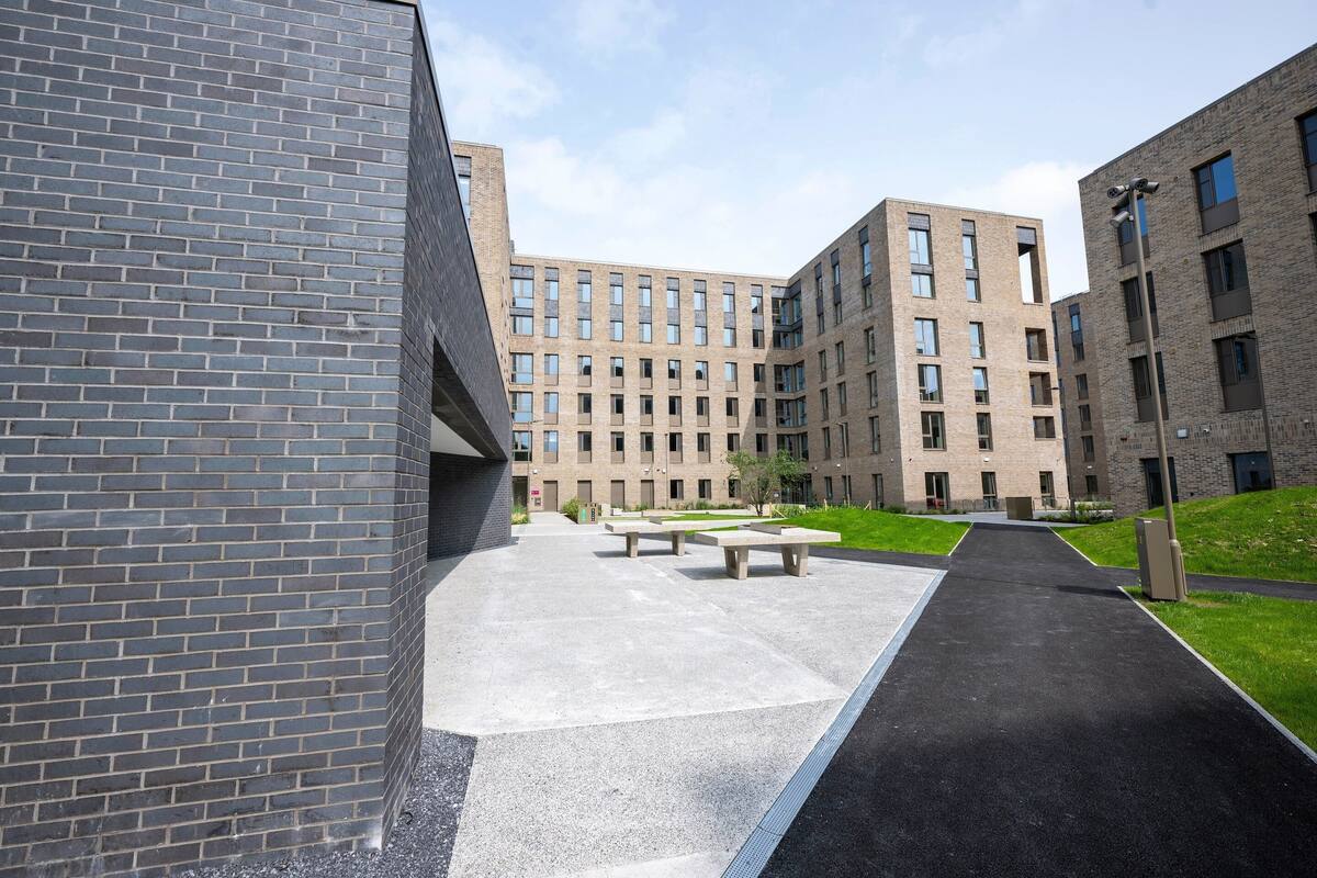 A modern building with a brick facade, a paved walkway, and outdoor seating areas.
