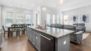 A modern kitchen with granite countertops, a central island, and a dining area with wooden chairs.