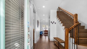 A hallway with a wooden staircase, a bench, and a door with a window.
