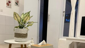 A modern bathroom with a wooden vanity, a potted plant, and a tissue box. - Seabreeze Hostel Bali (Canggu)