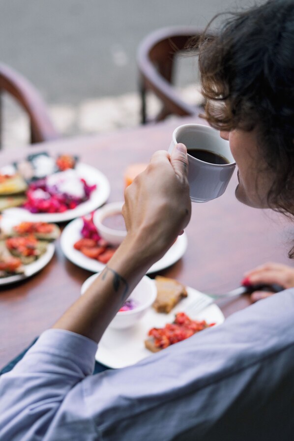 Una persona sentada a una mesa con platos de comida y una taza de café.
