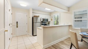 Una cocina moderna con una isla central, electrodomésticos de acero inoxidable y un comedor con mesa y sillas.