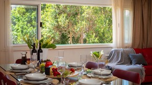A dining area with a table set for four, a red sofa, and a window with a view of trees. - Luxury Apartment Luft Split Near Old Town (Split)