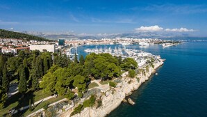 A coastal cityscape with a marina, buildings, and a cliff with dense greenery. - Luxury Apartment Luft Split Near Old Town (Split)