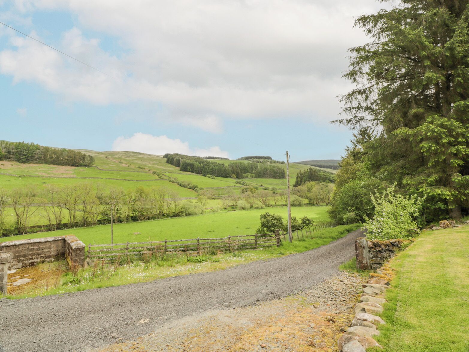 A rural road curving through a green landscape with stone walls and fences.