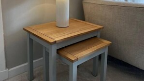 A small wooden nightstand with a white lamp and a matching bench. - Cosy Cottage Apartment (Argyll and Bute Council)