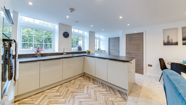 A modern kitchen with a herringbone floor pattern, large windows, and a view of greenery outside. - Spacious & Modern 2-Bedroom House (Worksop)