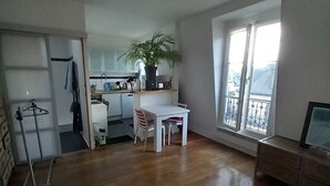 Un espacio habitable abierto con zona de comedor, un banco tapizado rojo y un amplio ventanal con vistas.