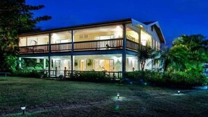 Un immeuble de deux étages doté d’un balcon à l’étage supérieur, entouré de verdure.
