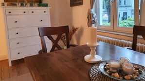 A dining area with a wooden table, a white cabinet with drawers, and a window with a view of buildings. - Living in the Mayor‘s Mansion (Hamburg)