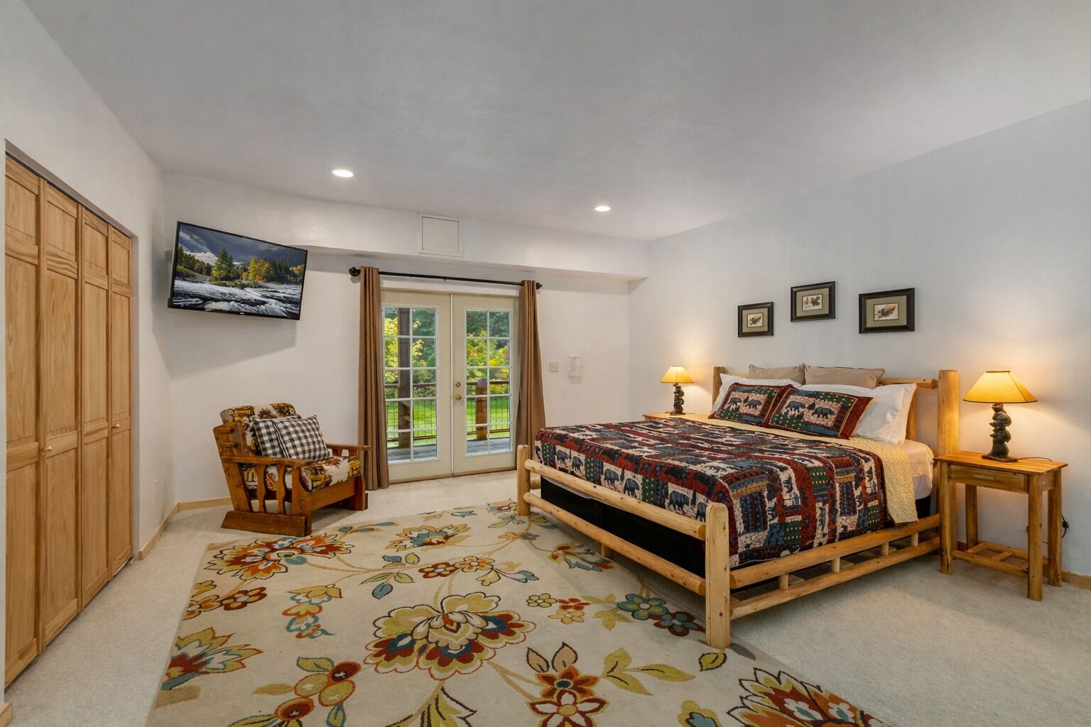 A bedroom with a bed, a wooden chair, a TV, and a door leading to a balcony.