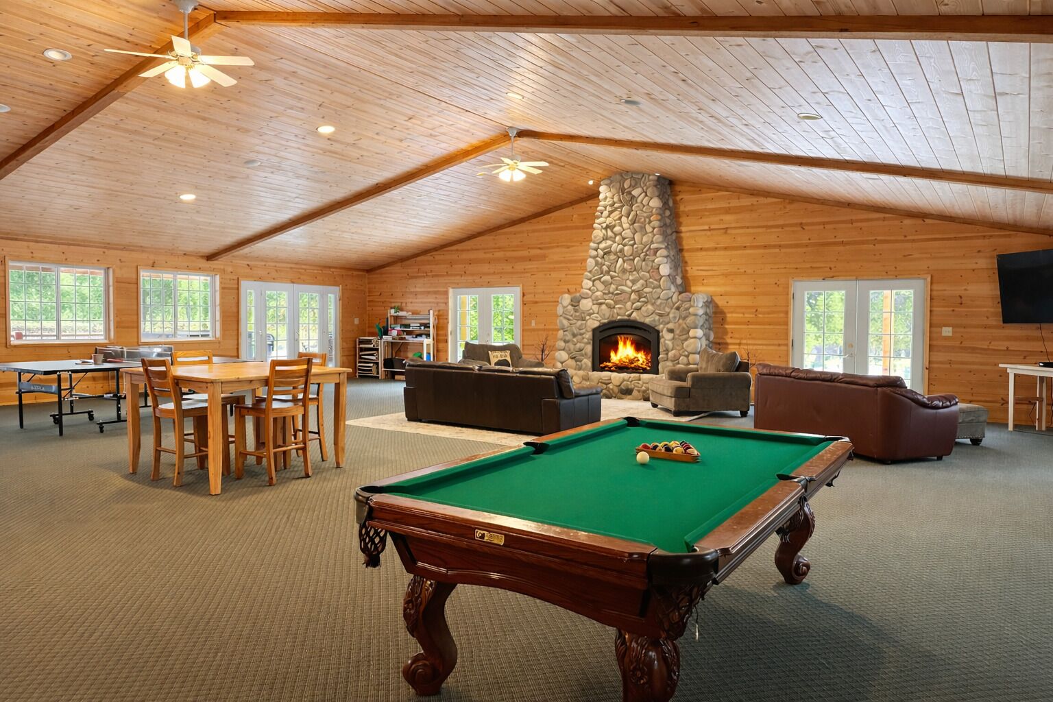 A spacious indoor area with a pool table, seating, a fireplace, and a television.