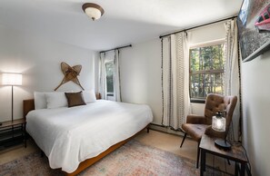 A bedroom with a large bed, a chair, a lamp, and a window with curtains. - Red Feather Chateau: Close To Town/Slopes & Dog Friendly (Breckenridge)