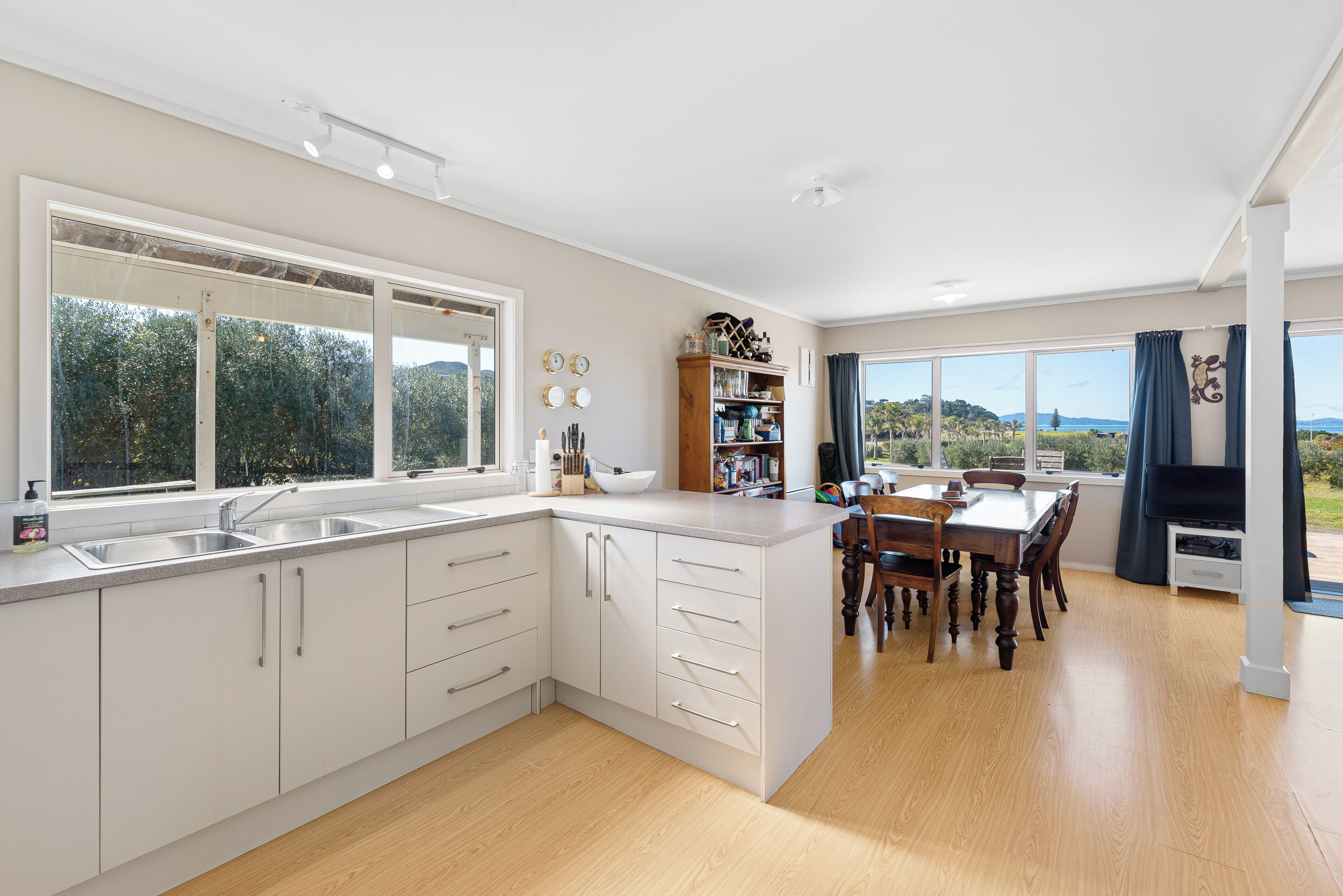 A modern kitchen with white cabinetry, a large island, and a dining area with wooden chairs.