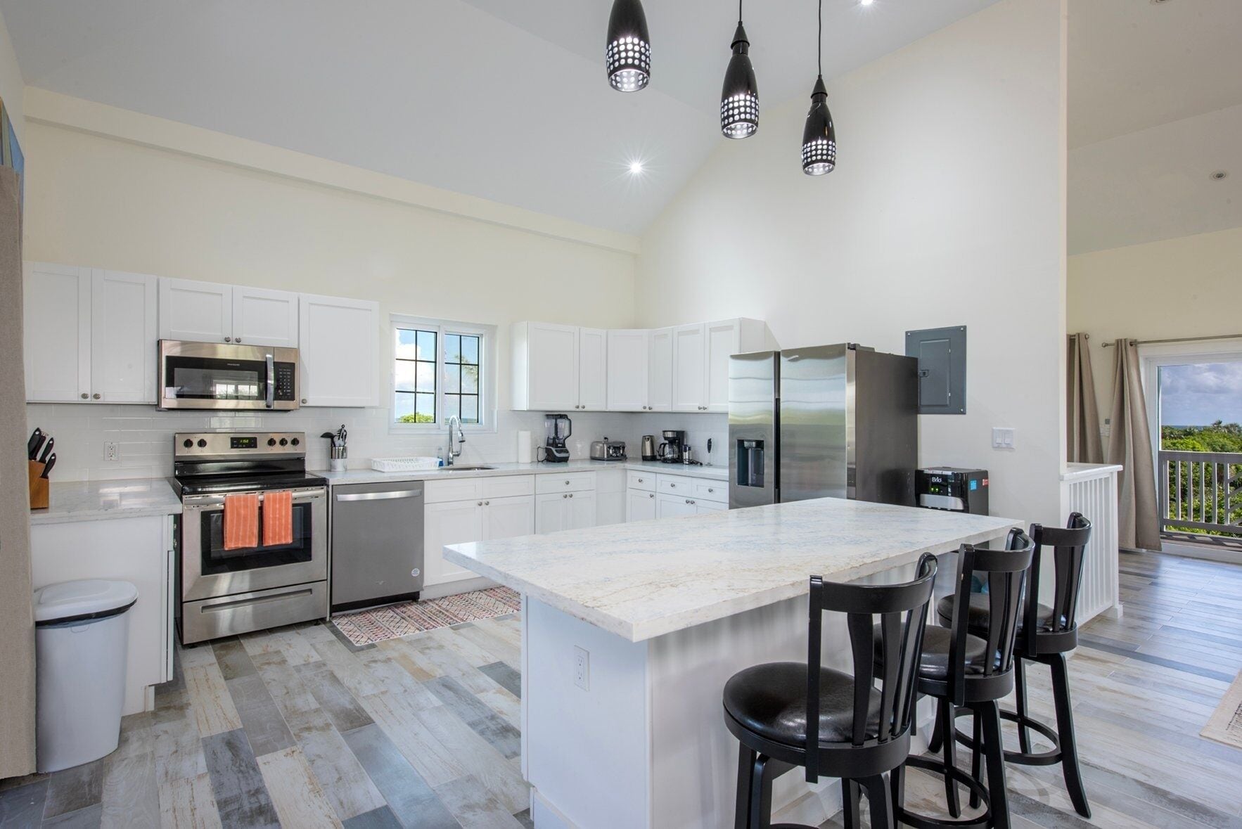 A modern kitchen with white cabinets, stainless steel appliances, and a large island with bar stools.