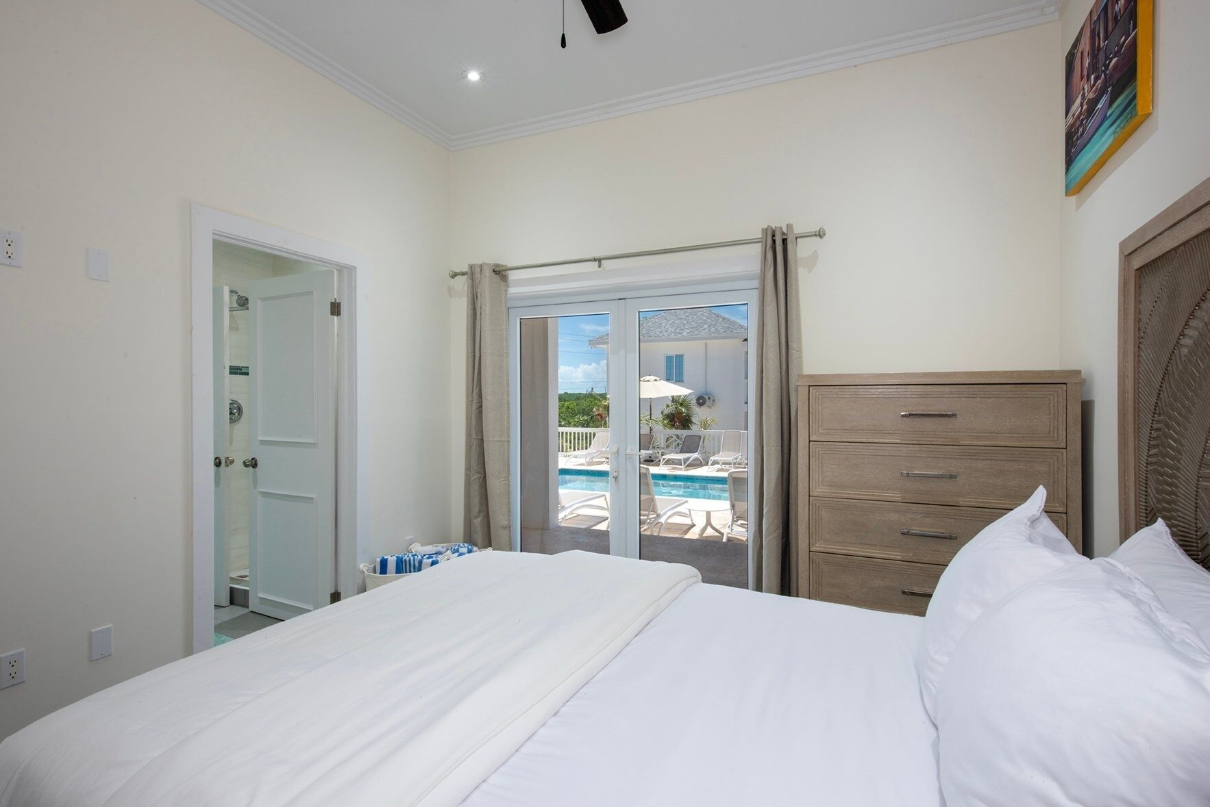 Une chambre avec un lit, une commode en bois et une vue sur une piscine et un espace de détente extérieur.