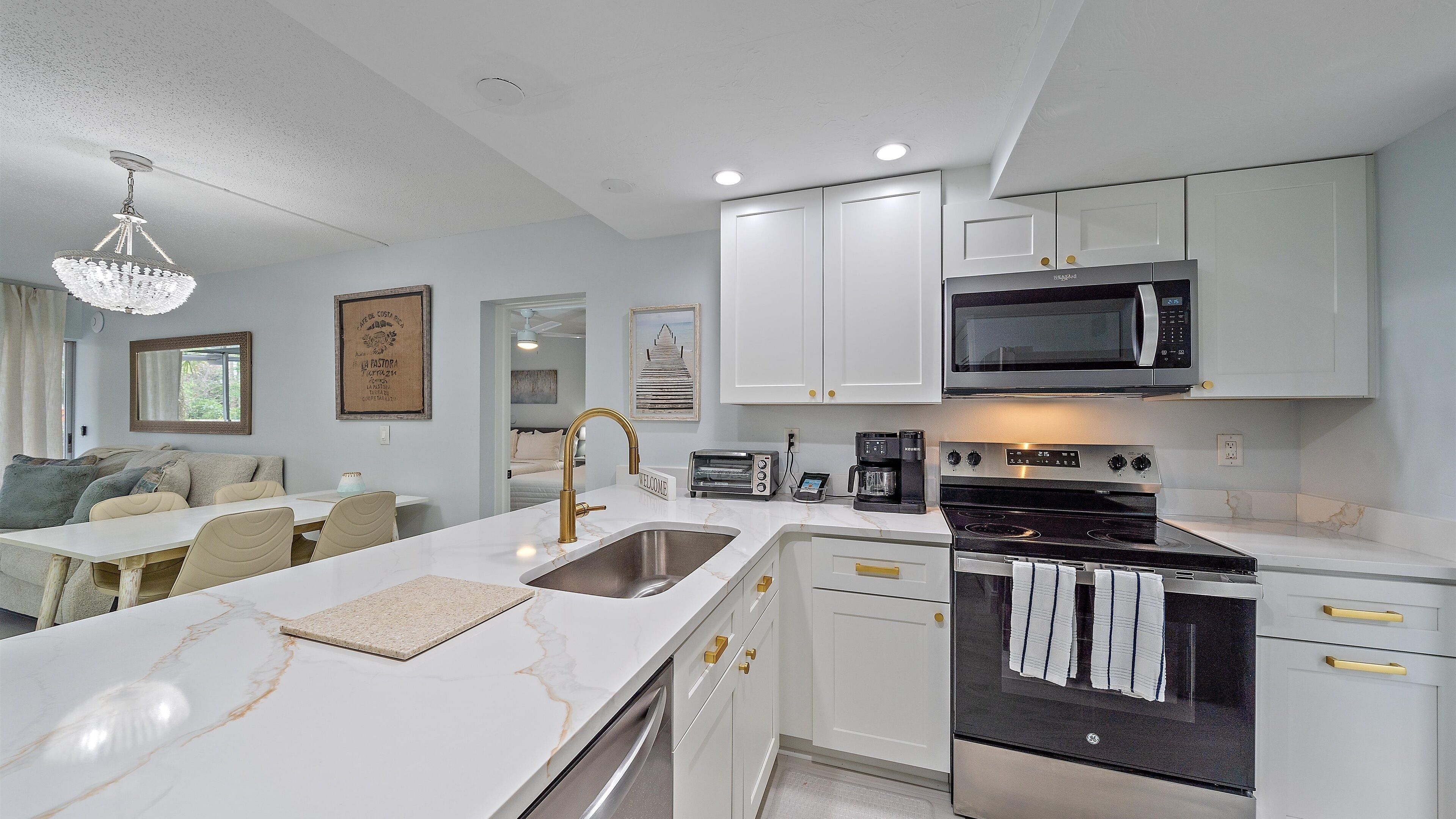 A modern kitchen with white cabinetry, a stainless steel stove, and a microwave.