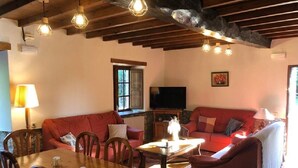 Una sala de estar acogedora con una mesa de comedor de madera, sofás rojos y una chimenea.