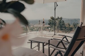 Una terraza con mesa y sillas, una botella de champán y vistas al campo.