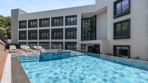 A modern building with a swimming pool, multiple windows, and outdoor seating. - INVENTIST Hotel Sports Academy (Çekmeköy)